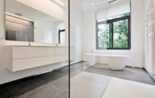 Bathtub in corian, Faucet and shower in tiled bathroom with windows towards garden